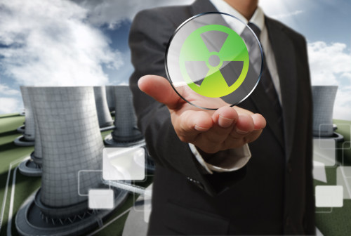 business man hand shows nuclear sign and nuclear power plant background